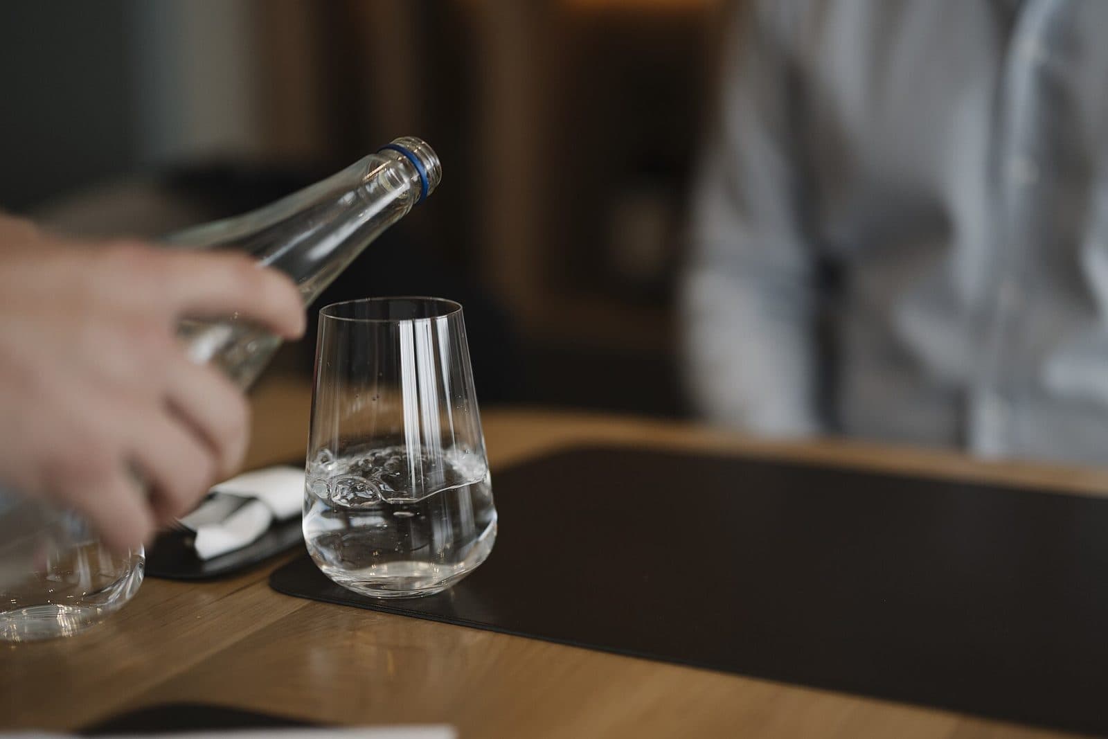 Wasser wird am Tisch in ein Glas eingeschenkt