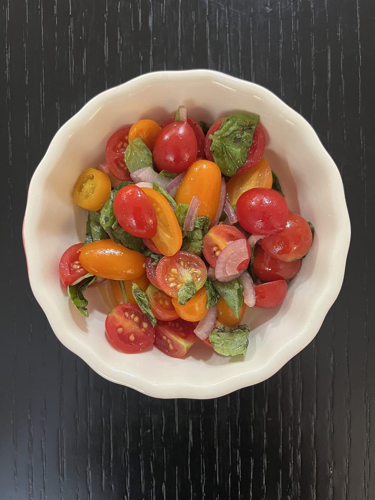 Tomatensalat mit Kirschtomaten und Kräutern in einer weißen Schale